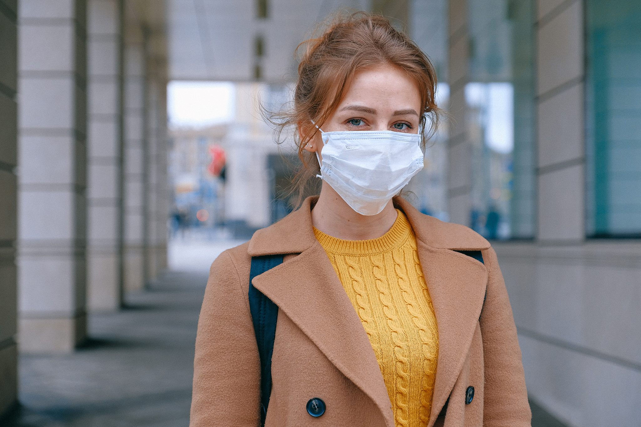 young woman wearing mask outside of building
