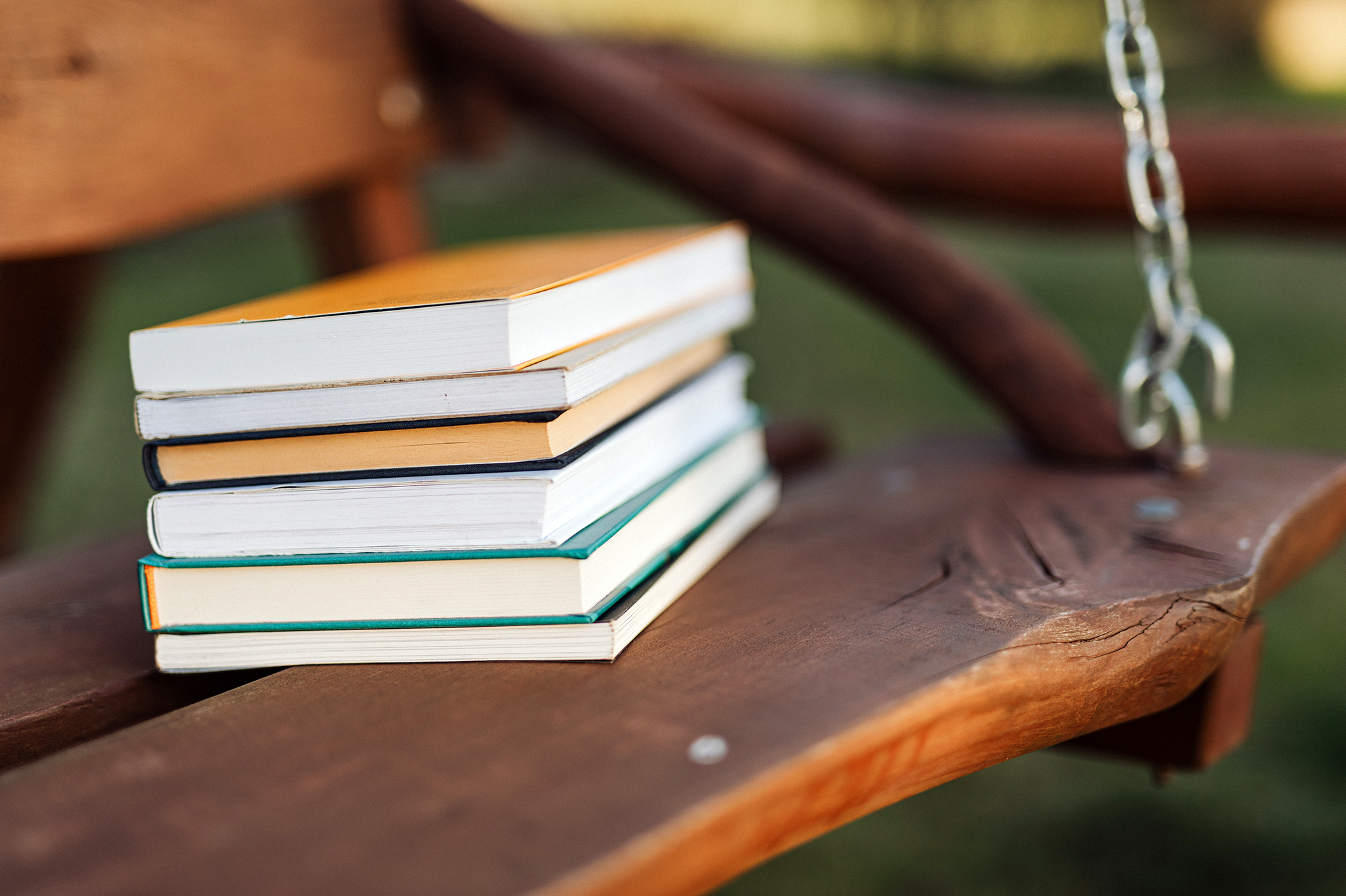 stack of books outside on wooden swing