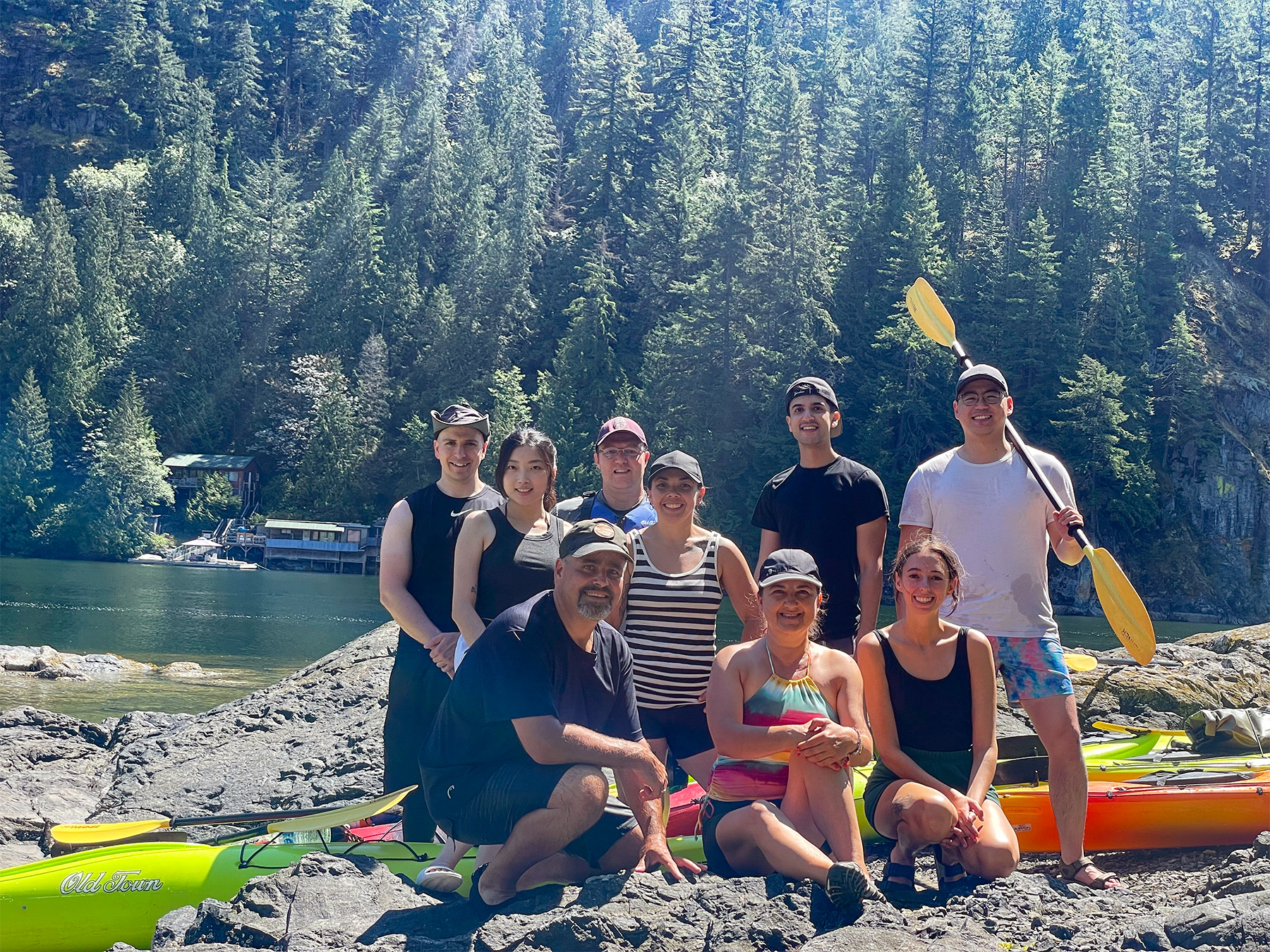 Team photo in front of deep cove with kayaks